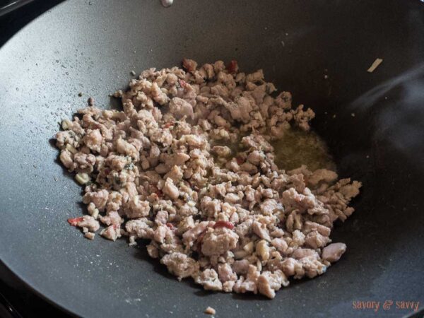 In a work or large pan over medium high heat, add sausage meat and brown until just cooked about 5-7 minutes. Then add garlic and stir for about 1 more minute.